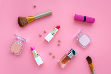 Set of pink cosmetics. Lipstick, bulk, eyeshadow, perfume near brushes on pink background top view