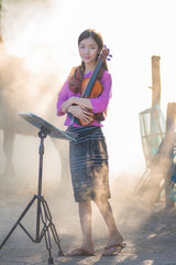 Music,melody,song concept. Asian beautiful girl playing a violin with happiness. Women enjoy playing music