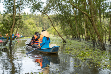 Fototapeta na wymiar Tourism rowing boat in cajuput forest in floating water season in Mekong delta, Vietnam