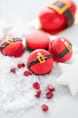 Funny cookie in the form red santa belly on gray table sprinkled with snow. Modern european French cuisine. Christmas theme, Merry Christmas card. New year mood. Variety of sweet macaroons.