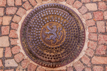 Ornate manhole cover with the Czech and Bohemian coat of arms with a lion in Prague, Czech Republic