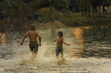 Two Asian boys friends running,playing in the water in summer sunny day.Freedom of life. friendship and freedom concept. 