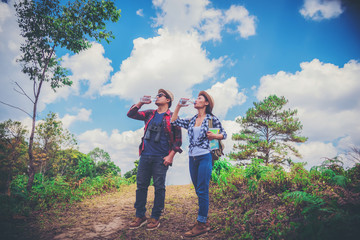 Fototapeta premium Young couple hiking tourist with backpack drinking water in nature.