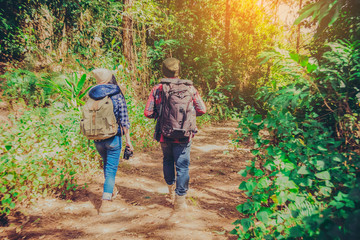 Obraz premium Young couple hiking tourist with backpack drinking water in nature.
