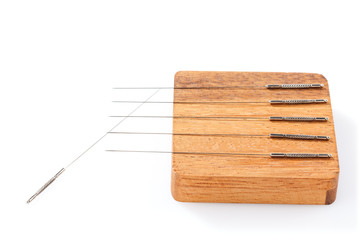 Silver acupuncture needles, on a wooden stand, isolated on a white background. Close-up