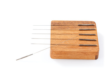 Silver acupuncture needles, on a wooden stand, isolated on a white background. Close-up