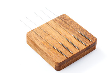 Silver acupuncture needles, on a wooden stand, isolated on a white background. Close-up