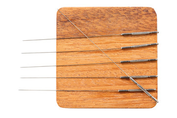 Silver acupuncture needles, on a wooden stand, isolated on a white background. Close-up