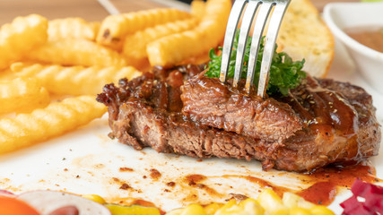 Beefsteak, French fries, and vegetable on a white plate.