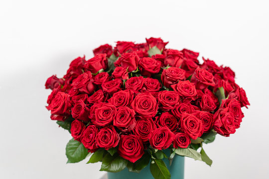 Big luxury bright bouquet on wooden table. One hundred of garden red roses. Color passionately scarlet, Autumn mood. bouquet in a hat box