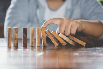 Obraz na płótnie Canvas Businessman hand stopping falling wooden dominoes effect from continuous toppled or risk, strategy and successful intervention concept for business, game strategy, Invesment and Risk Management.