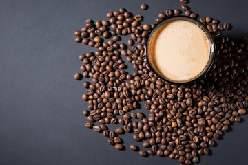 roasted grains and a cup of aromatic coffee on a table in a dark manner with side-mounted light