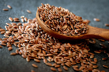 Close up a flax seeds in spoon on black stone , superfood with rich of omega 3 , heart healthy food