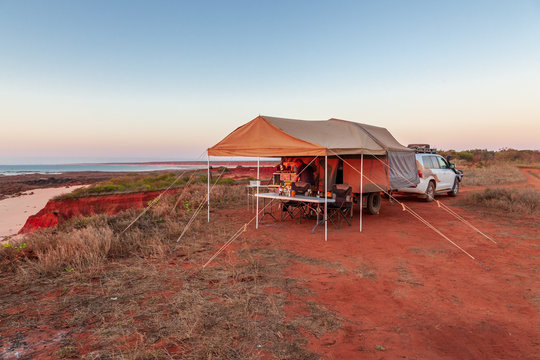 Man preparing a meal in Offroad camper trailer while camping on top of the red cliffs at James Price Point in the late afternoon in the Kimberley Region of Western Australia.