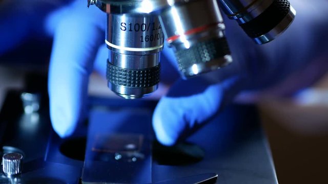 Scientist hands with microscope close-up shot in the laboratory. Medical laboratory research tools in the hands in gloves. Close up. Forensic examination. 4K UHD..