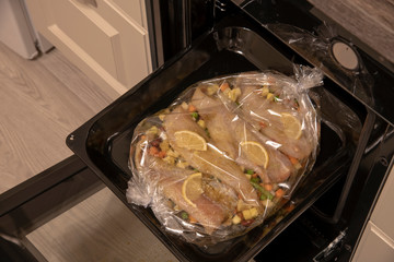 White fish with lemon and vegetables in sleeve for baking