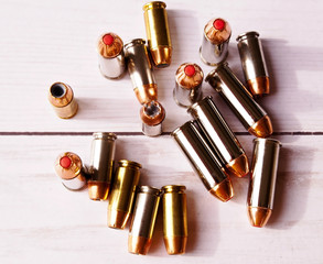 Nine 40 caliber hollow point bullets and eight 44 special bullets with red tips shown on a wooden...