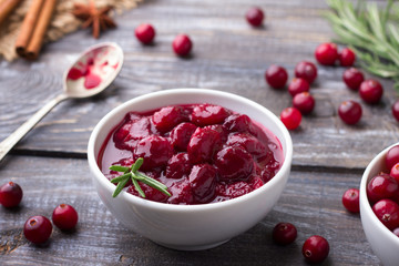 Homemade spicy cranberry sauce with fresh cranberries, cinnamon and star anise on a wooden background
