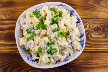 Traditional Russian festive salad Olivier on wooden table. Top view