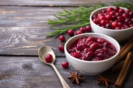 Homemade spicy cranberry sauce with fresh cranberries, cinnamon and star anise on a wooden background, free space