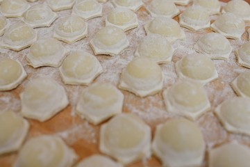 Fototapeta na wymiar culinary background-raw dumplings or ravioli on wooden background