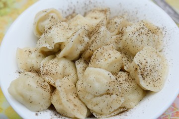 appetizing fresh Russian dumplings or pelmeni sprinkled with black pepper close up