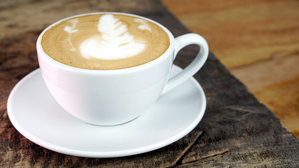 Cappuccino or latte art coffee. Free hand pouring some foam of milk on top. A white ceramic cup on the wood table with some coffee beans. The best food and drink in the world. Fresh energy everyday.