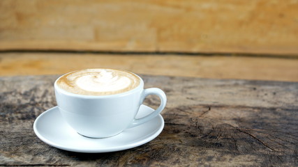 Cappuccino or latte art coffee. Free hand pouring some foam of milk on top. A white ceramic cup on the wood table with some coffee beans. The best food and drink in the world. Fresh energy everyday.