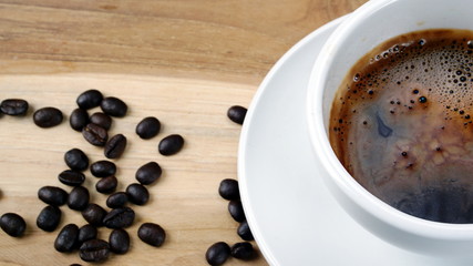 Americano or espresso coffee on the wood table with roasted coffee beans