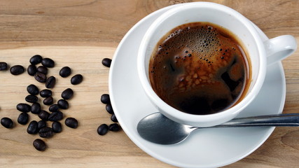 Americano or espresso coffee on the wood table with roasted coffee beans