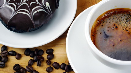 Americano or espresso coffee on the wood table with roasted coffee beans