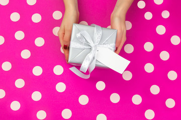 Obraz na płótnie Canvas Woman hands holding gift box on pink background