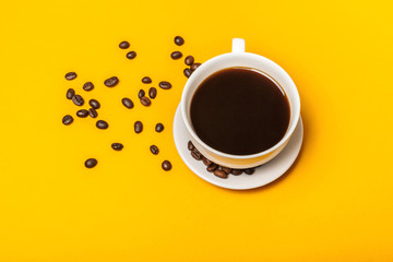 Spilled coffee beans on a bright yellow background