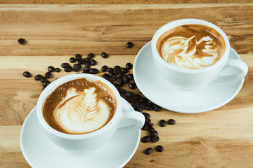 Cappuccino and latte art on the wood table. Free hand pouring some milk on the coffee. Morning breakfast with coffee.