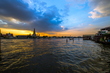 Fototapeta premium Wat Arun Ratchawararam Ratchawaramahawihan- Bangkok: Location at Chao Phraya River cruise tourists, dining on the boat and watch the evening light on the river, in Phranakhon, Thailand