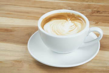 Cappuccino or latte art coffee. Free hand pouring some foam of milk on top. A white ceramic cup on the wood table with some coffee beans. The best food and drink in the world. Fresh energy everyday.