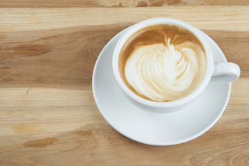 Cappuccino or latte art coffee. Free hand pouring some foam of milk on top. A white ceramic cup on the wood table with some coffee beans. The best food and drink in the world. Fresh energy everyday.