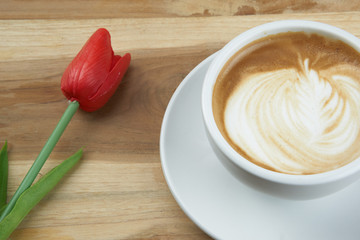Cappuccino or latte art coffee. Free hand pouring some foam of milk on top. A white ceramic cup on the wood table with some coffee beans. The best food and drink in the world. Fresh energy everyday.
