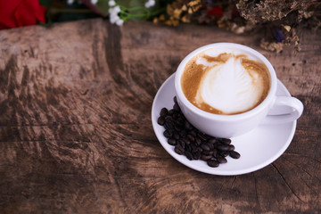 Cappuccino or latte art coffee. Free hand pouring some foam of milk on top. A white ceramic cup on the wood table with some coffee beans. The best food and drink in the world. Fresh energy everyday.