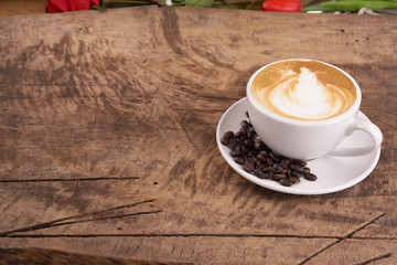Cappuccino or latte art coffee. Free hand pouring some foam of milk on top. A white ceramic cup on the wood table with some coffee beans. The best food and drink in the world. Fresh energy everyday.