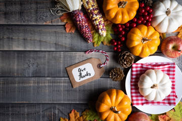 Top view of  Autumn maple leaves with Pumpkin, apple, corn and red berries on old wooden background. Thanksgiving day concept.