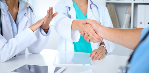 Two doctors shaking hands to each other at meeting. Teamwork and agreement in medicine