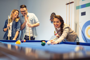 Coworkers playing a game pool after a long work day.