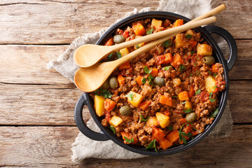 Delicious Picadillo cooked from ground beef with vegetables, raisins and spices close-up in a...