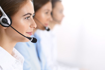 Call center. Group of operators at work. Focus at beautiful business woman in headset