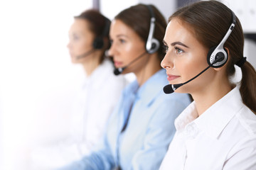 Call center. Group of operators at work. Focus at beautiful business woman in headset