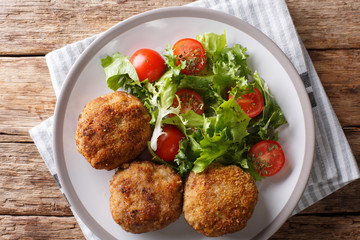 Karbonader Breaded Pork Patty Recipe with fresh vegetable salad close-up on a plate. horizontal top view