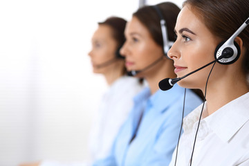 Call center. Group of operators at work. Focus at beautiful business woman in headset