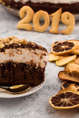 A piece of holiday dessert. Figures 2019. Chocolate cake with white meringue. Dried fruit slices. Light background.