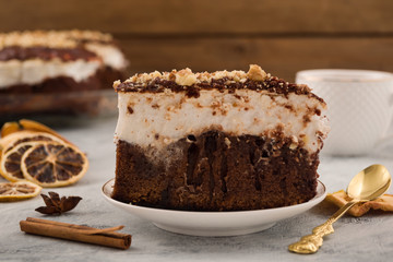 A piece of chocolate meringue pie. Cinnamon stick, dried lemon slices. Metal teaspoon. Light background.